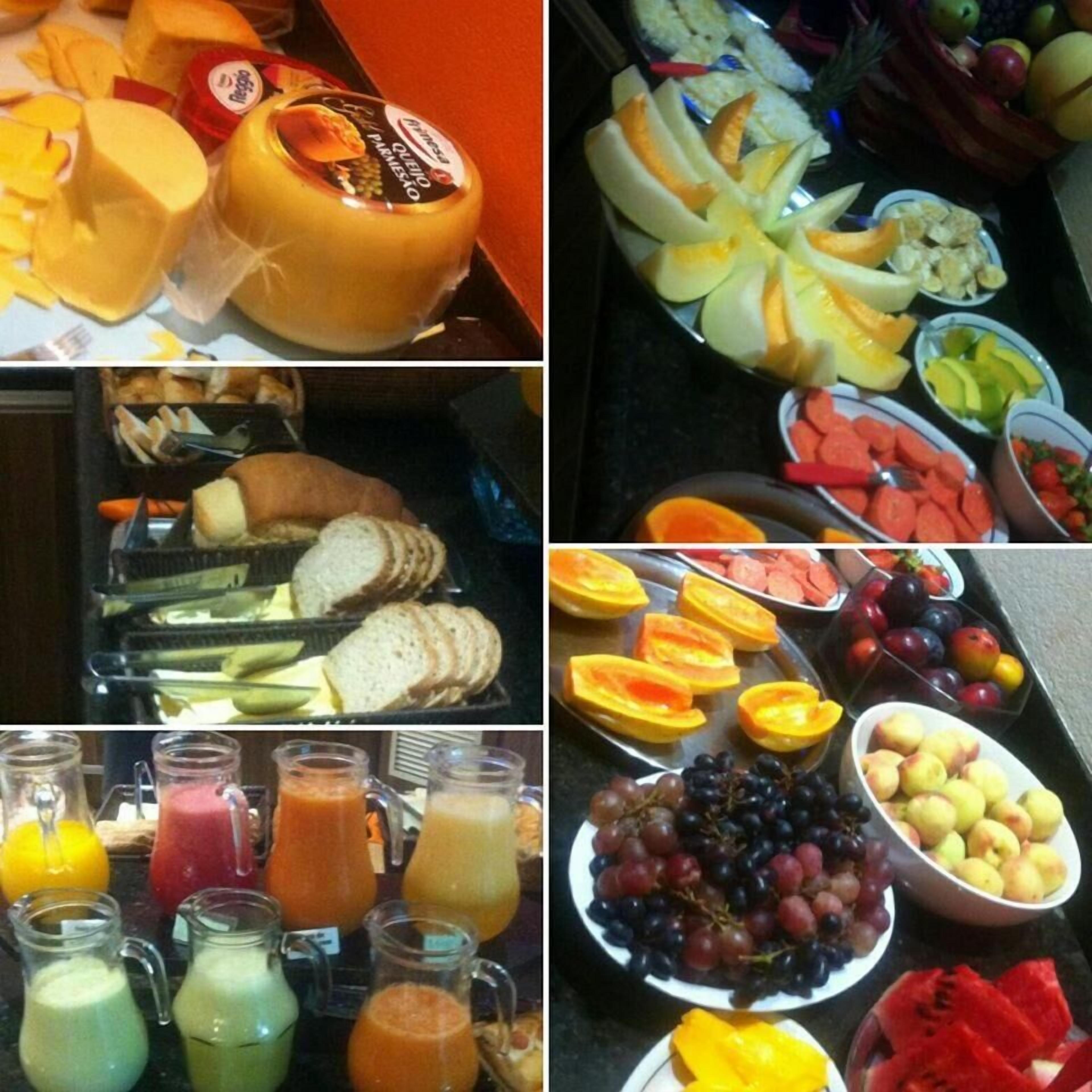 A buffet with cheese, fruits, bread, and various juices.