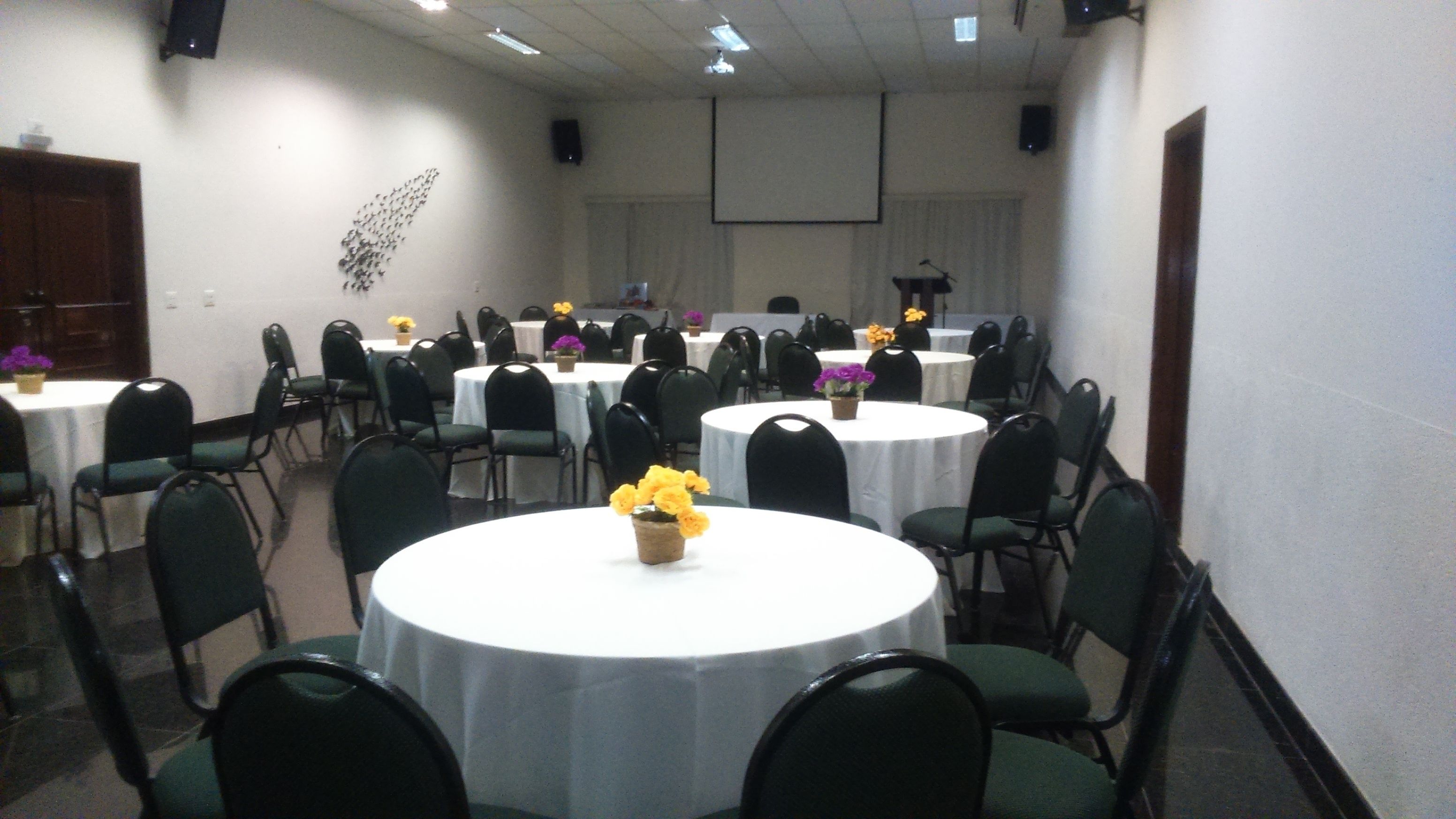 Un salón de conferencias con varias mesas redondas, cada una rodeada de sillas.