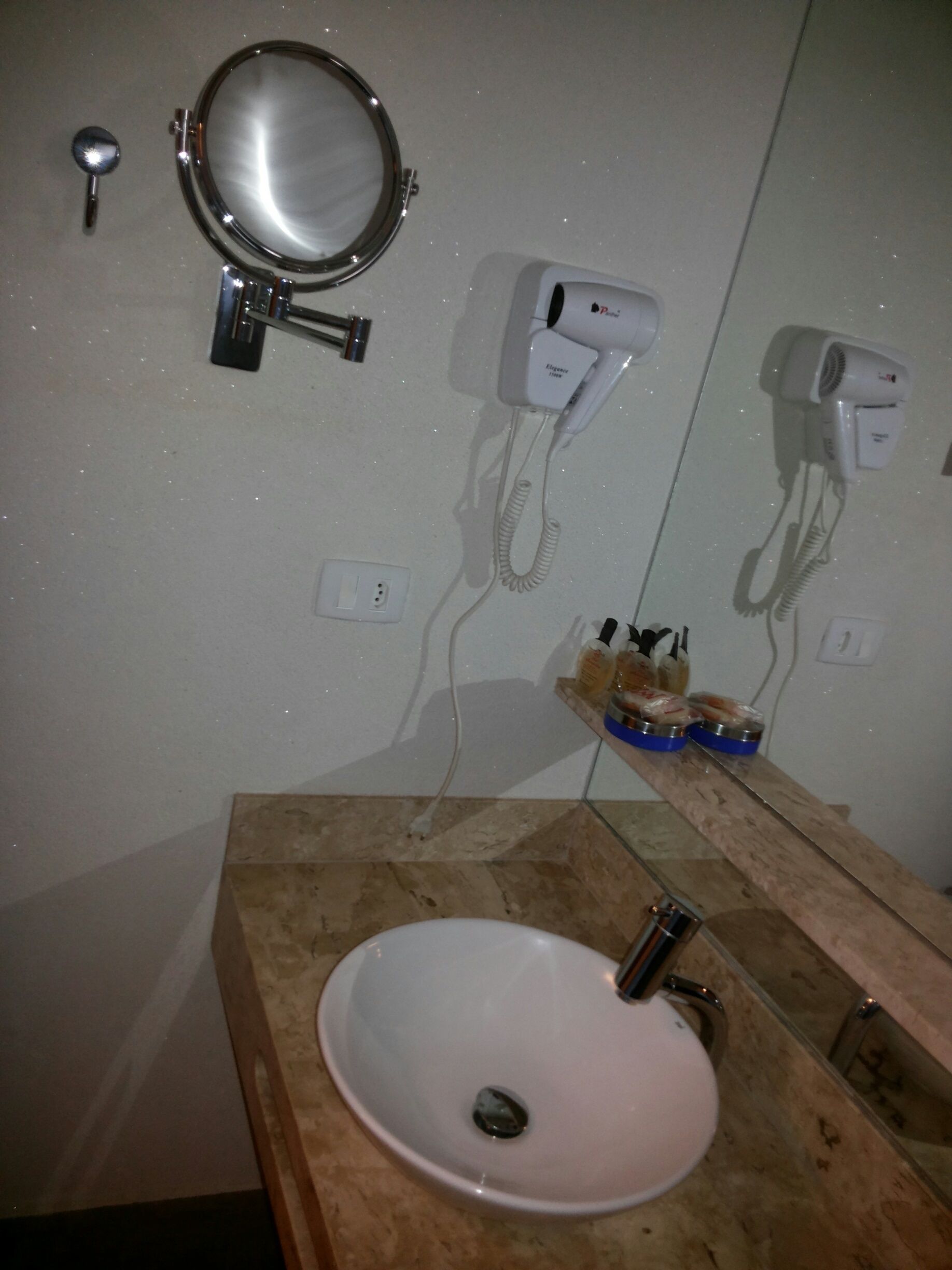 Un baño con lavabo, espejo y secador de pelo.