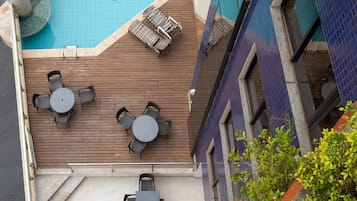 Una piscina al aire libre, sombrillas, sillones reclinables de piscina