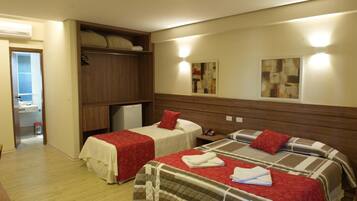 A hotel room with two beds, a wardrobe, a small desk, and a wall-mounted artwork.