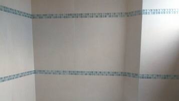 A bathroom with a freestanding bathtub, wooden paneling, and a tiled backsplash.