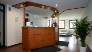 A reception area with a wooden counter, a black doormat, and a potted plant. - Hotel Sophienhof (Königs Wusterhausen)