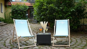 Two light blue chairs with 'SPREEQUELL' branding, a black woven table, and two glasses of wine. - Hotel Sophienhof (Königs Wusterhausen)