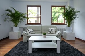 A modern living room with a sofa, a coffee table, and two potted plants. - Hotel Sophienhof (Königs Wusterhausen)
