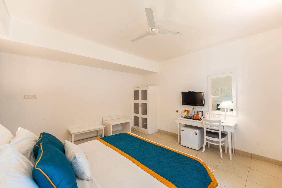 Ein Hotelzimmer mit Bett, Schreibtisch, Computer, Fernseher und Kleiderschrank.