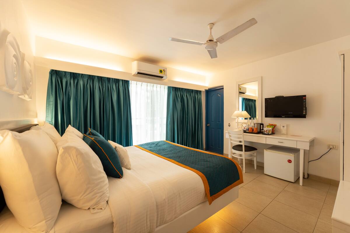 Ein Hotelzimmer mit Bett, Schreibtisch, Fernseher und Klimaanlage.