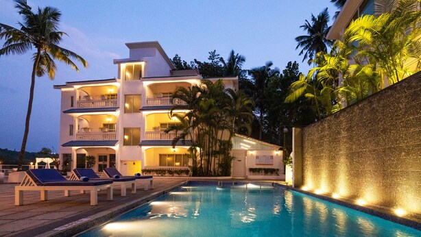 A multi-story hotel with a swimming pool, lounge chairs, and palm trees. - Zone Connect by The Park Goa Calangute (Calangute)
