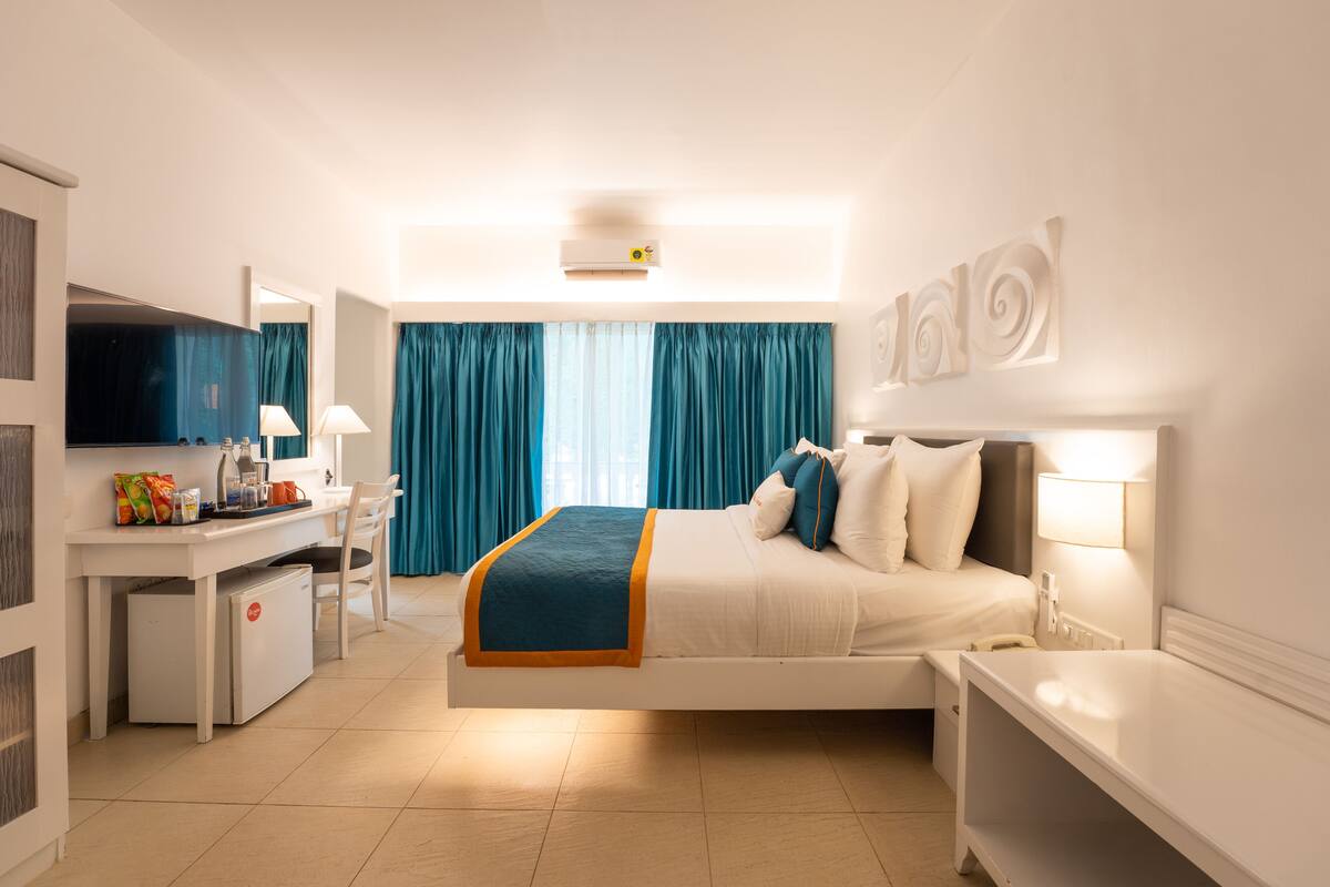 Ein Hotelzimmer mit Bett, Nachttisch, Schreibtisch, Stuhl und Fernseher.