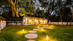 A well-lit outdoor area with a pathway leading to a building, surrounded by trees and illuminated by lanterns. - Zone Connect by The Park Goa Calangute (Calangute)