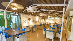 A spacious restaurant with high ceilings, wicker furniture, and a view of greenery outside. - Zone Connect by The Park Goa Calangute (Calangute)