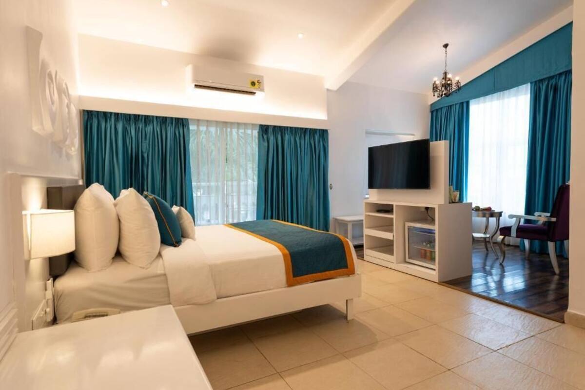 Ein modernes Hotelzimmer mit Bett, Fernseher, Sitzecke und Schreibtisch.