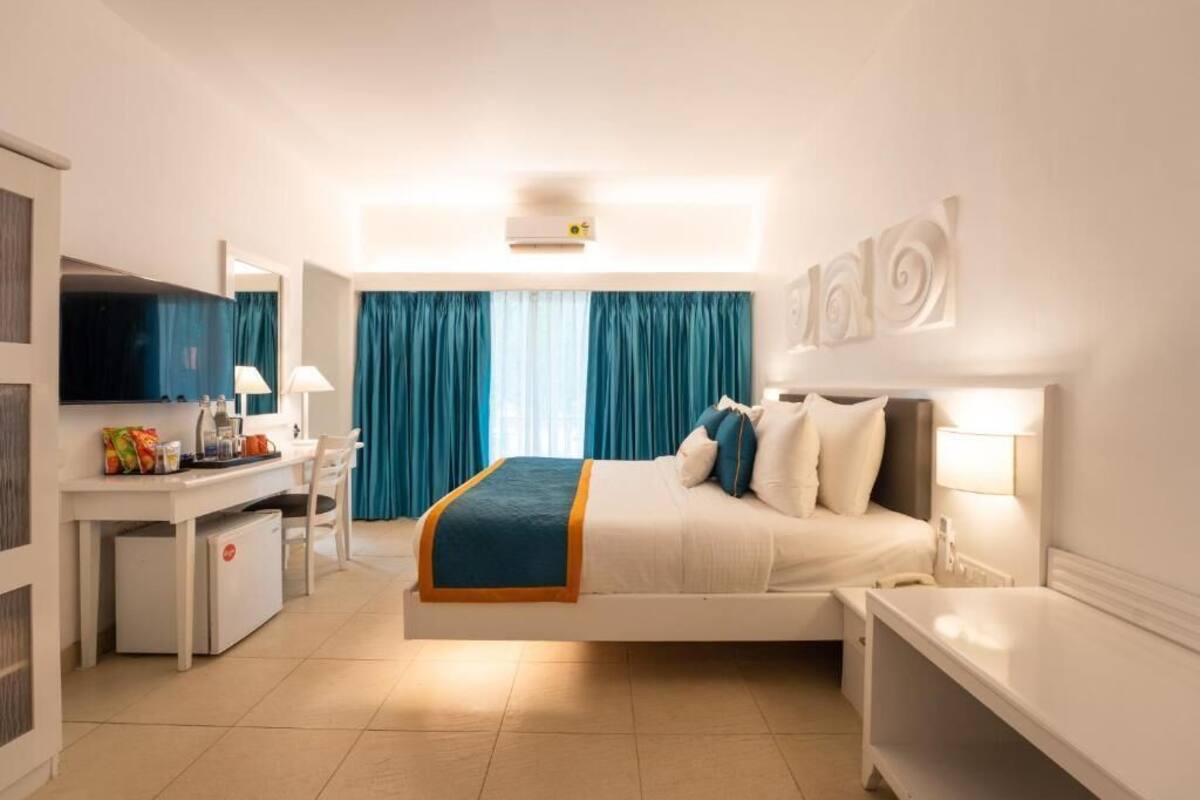Ein Hotelzimmer mit Bett, Schreibtisch, Stuhl und Fernseher.