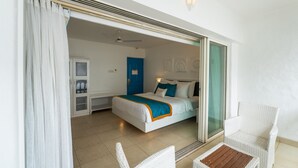 A hotel room with a bed, a chair, a small table, and a sliding door leading to a balcony. - Zone Connect by The Park Goa Calangute (Calangute)