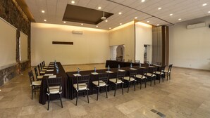 A conference room with a long table and chairs, a projector, and an air conditioning unit. - Hotel Villa Mexicana Golf Resort (Corregidora)