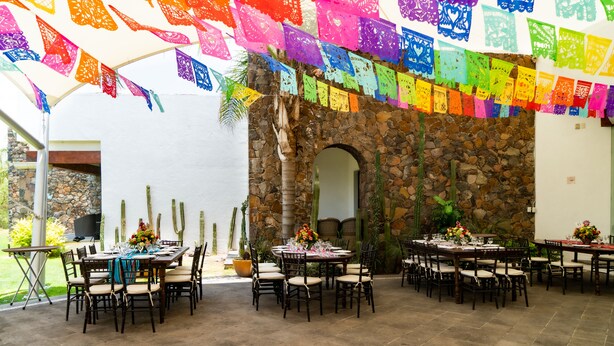 An outdoor dining area with stone walls, cactus plants, and tables set for dining. - Hotel Villa Mexicana Golf Resort (Corregidora)