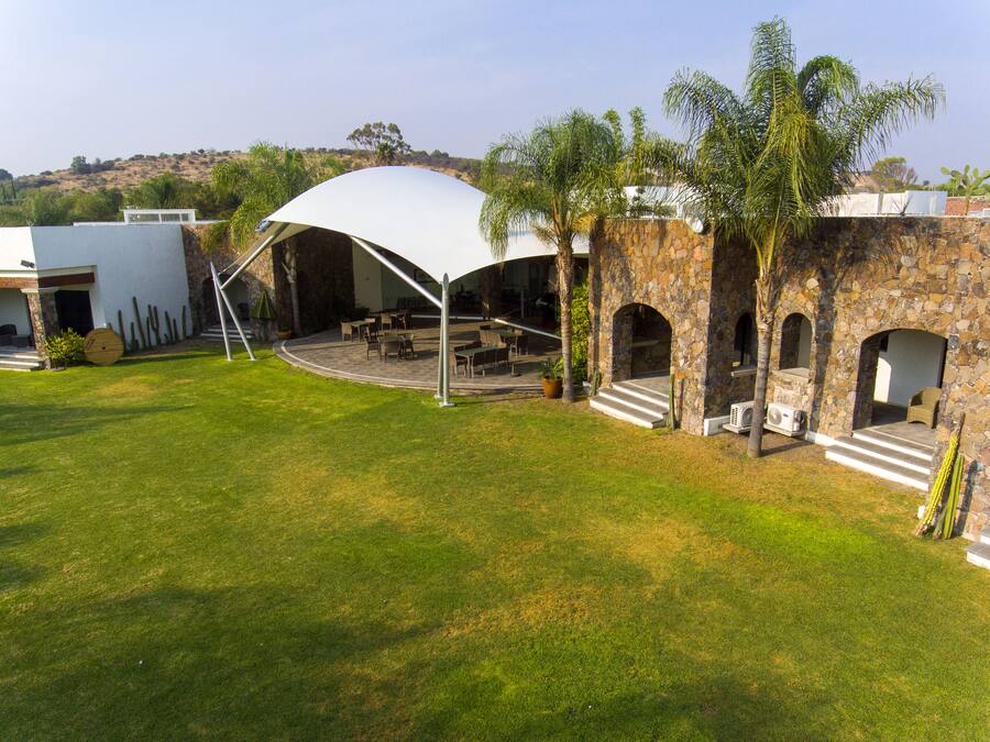 A covered outdoor seating area with stone walls and palm trees.