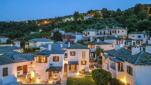 A cluster of white buildings with tiled roofs, some with balconies, set against a hillside. - Aeolos Hotel & Villas -Pelion (Zagora-Mouresi)