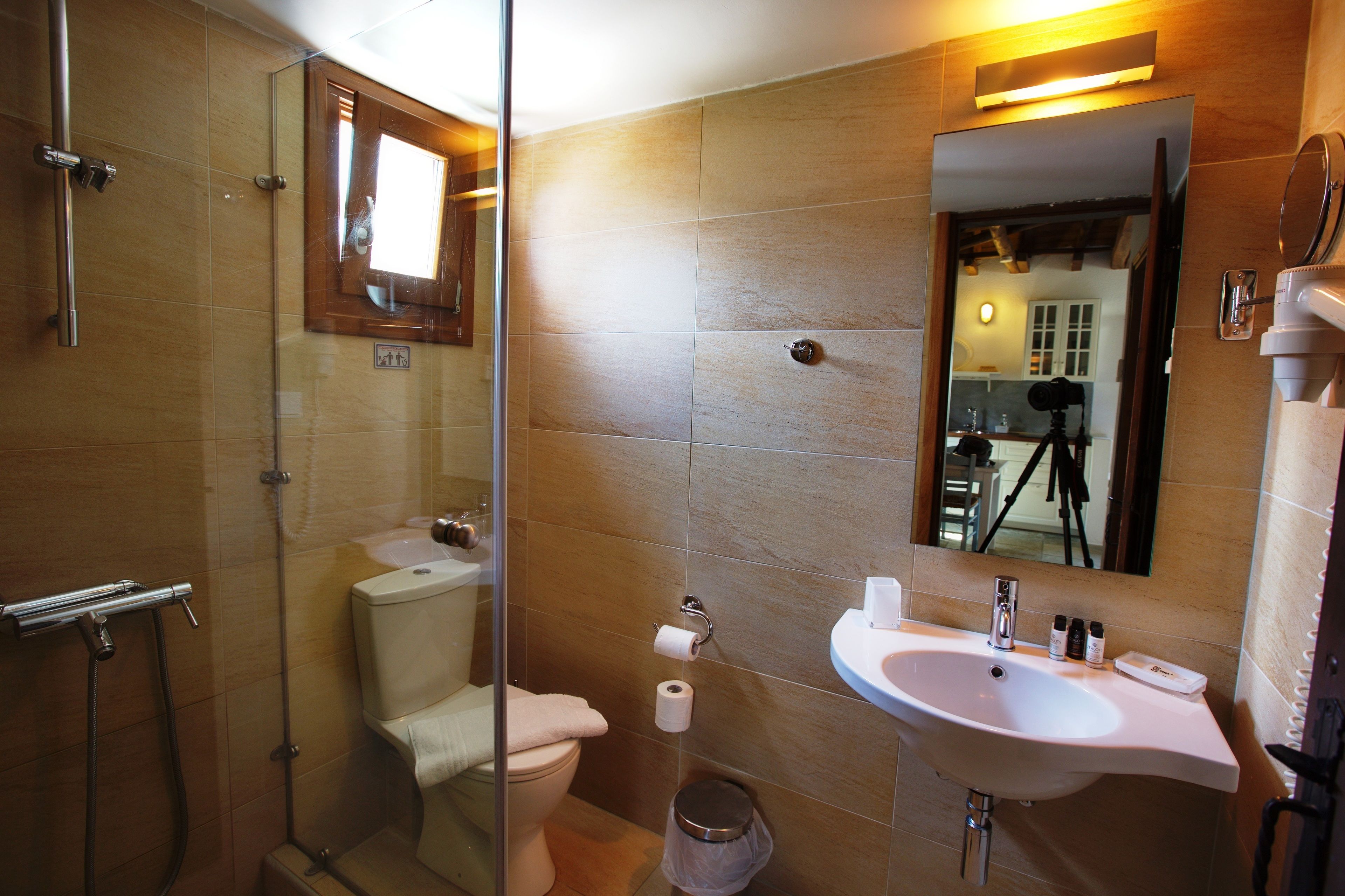 Een badkamer met een glazen douchecabine, een toilet en een wastafel met spiegel.