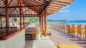 Eine Strandbar mit Holzsitzgelegenheiten und Blick auf das Meer.