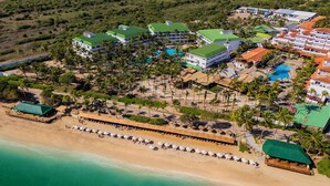 Eine Vogelperspektive zeigt ein Resort mit mehreren Gebäuden, einem Strand und einem Poolbereich.