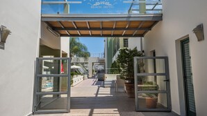 The entrance to Athina Beach Hotel with a clear sky, a covered walkway, and potted plants. - Athina Beach Hotel (Chania)