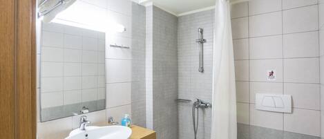 A bathroom with a sink, mirror, shower, and toilet.