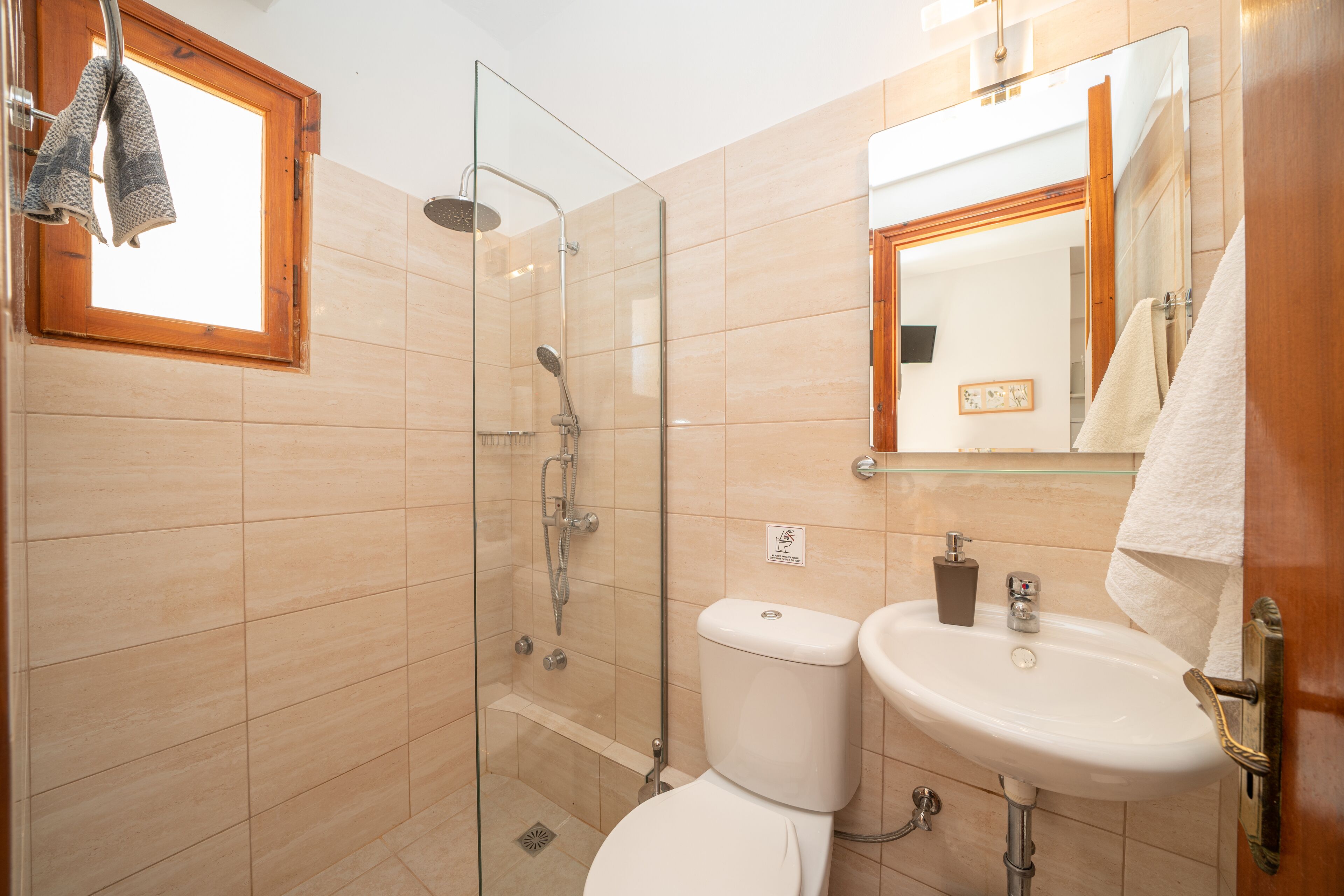 A bathroom with a glass-enclosed shower, a toilet, and a sink.