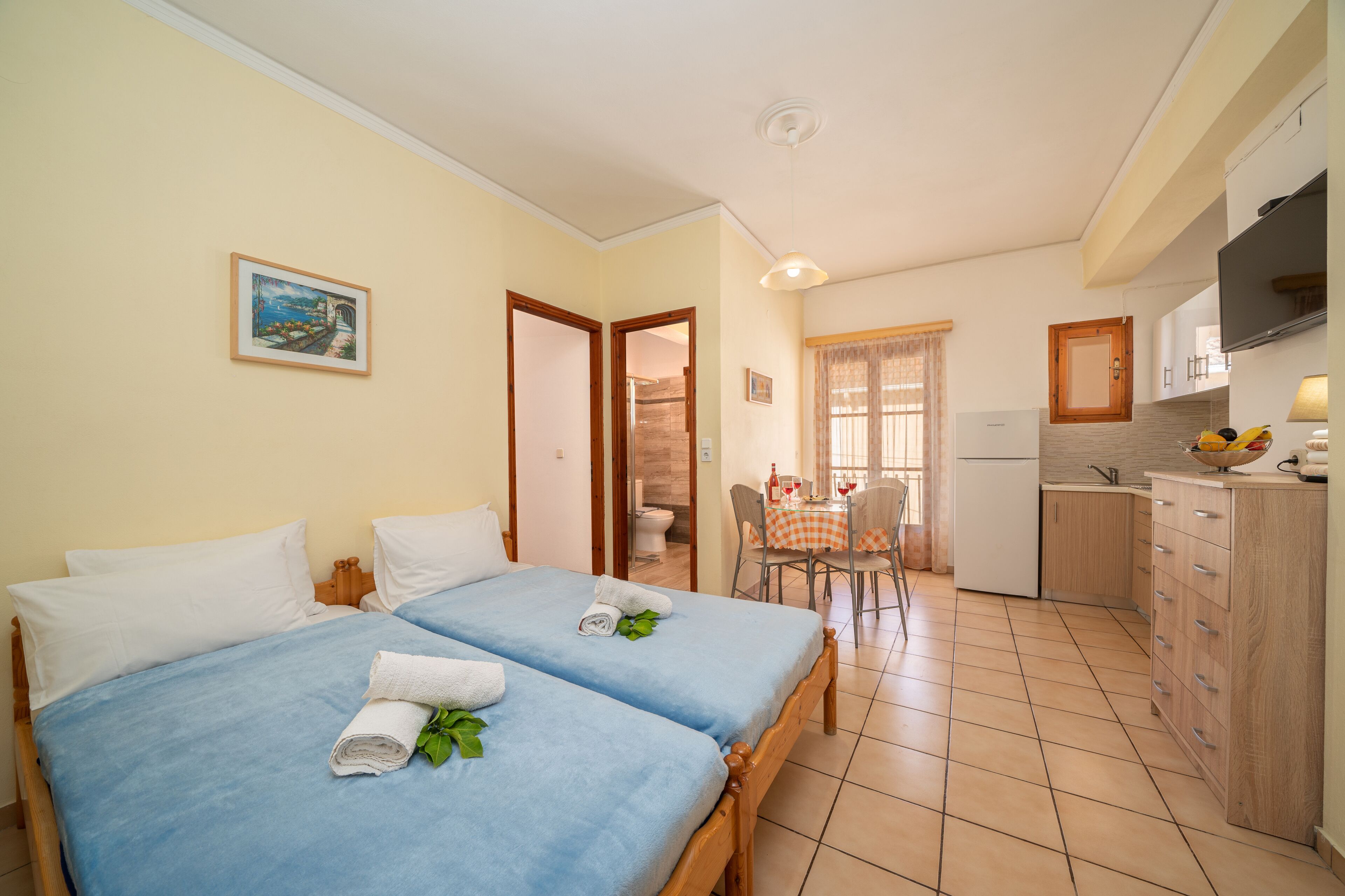 Ein Zimmer mit zwei Betten, einer kleinen Küche und einem Essbereich.