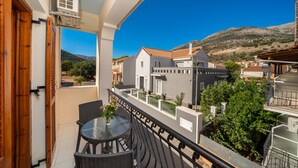 Ein Balkon mit Tisch und Stühlen, mit Blick auf ein Wohngebiet mit Häusern und einem Berg im Hintergrund.