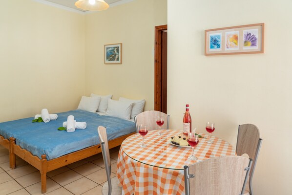 Un dormitorio con una cama, una mesa con mantel a cuadros y dos sillas. Hay toallas sobre la cama y una botella de vino sobre la mesa.