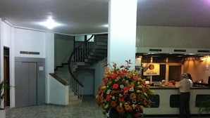 A hotel lobby with a staircase, a reception desk, and a large flower arrangement. - Hotel Betoma (Santa Marta)