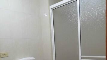 A bathroom with a toilet, a shower enclosure, and a sink.
