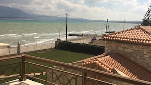 A coastal view with a stone building, a metal railing, and a clear sky.