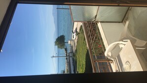 A view from inside a room looking out to a balcony with a railing, a statue, and a clear blue sky.