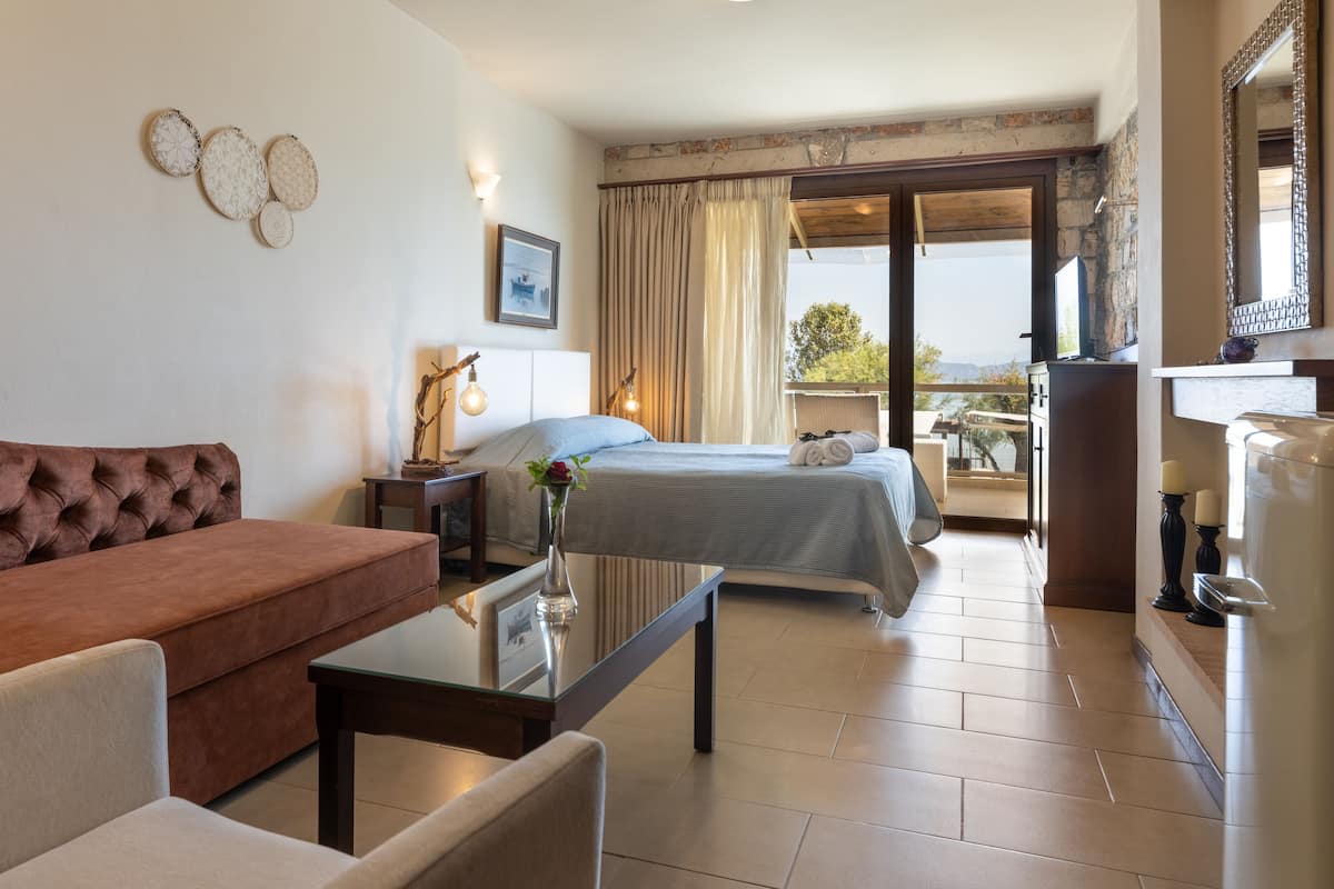 Ein Hotelzimmer mit Bett, einer Couch, einem kleinen Tisch und einem Balkon mit Aussicht.
