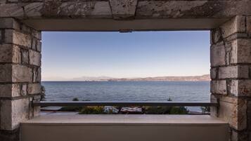 A stone-framed window overlooking a body of water with distant land.