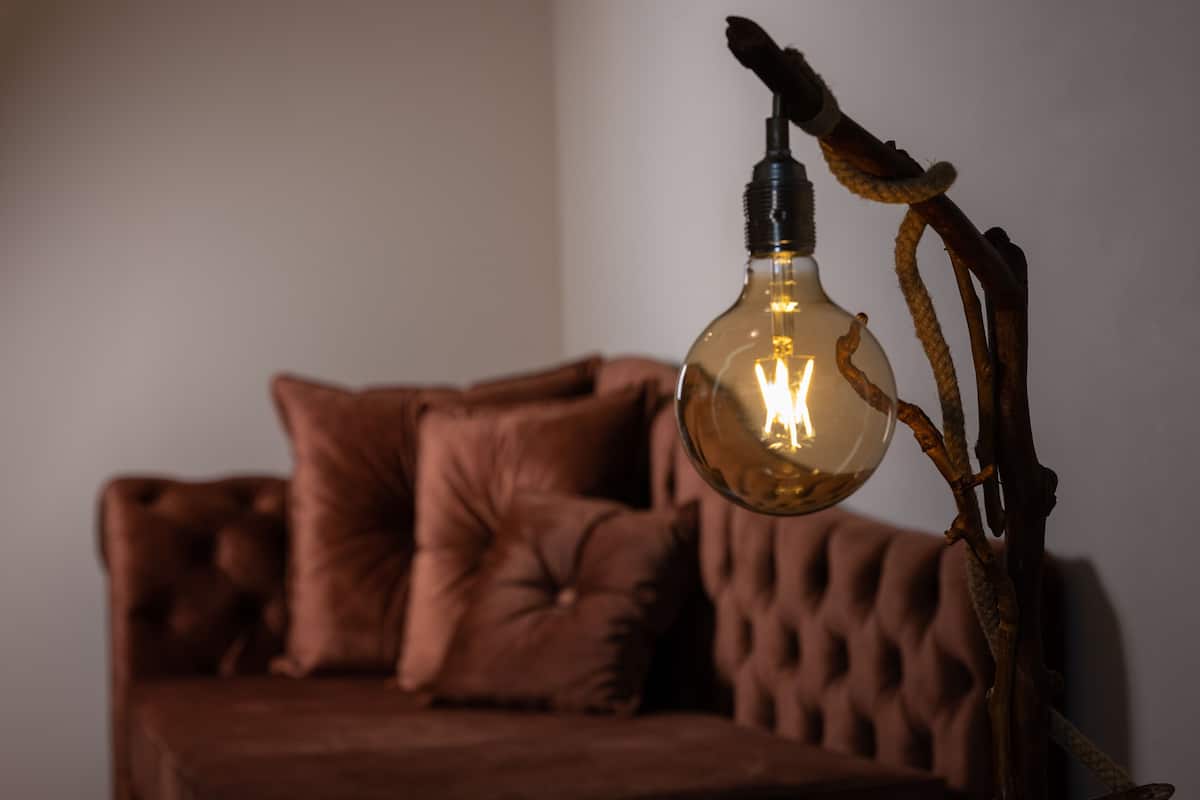 Ein Zimmer mit einer braunen Couch und einer besonderen Lampe.