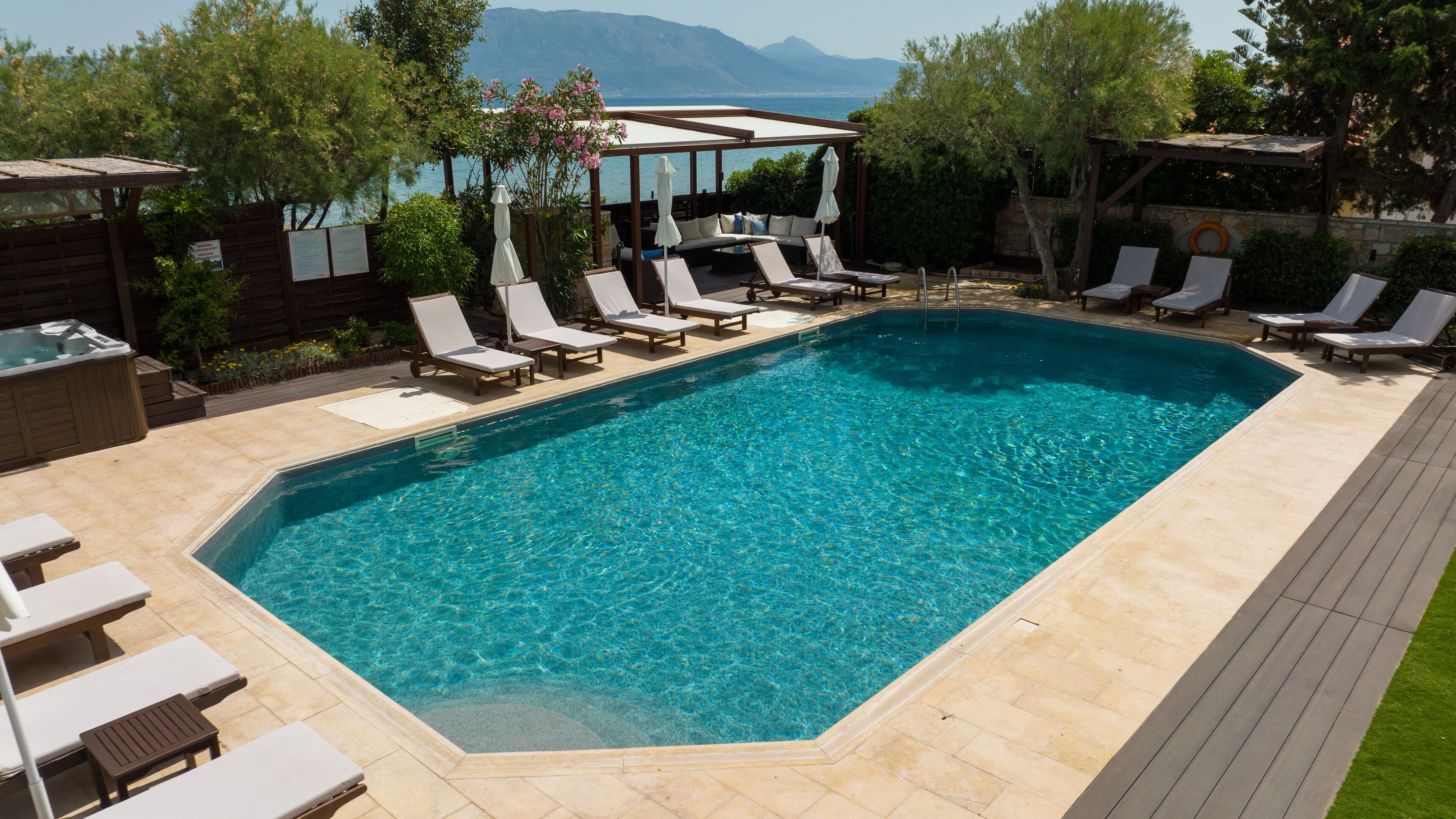 Une piscine rectangulaire à l’eau d’un bleu cristallin, entourée de chaises longues et d’une terrasse en bois.