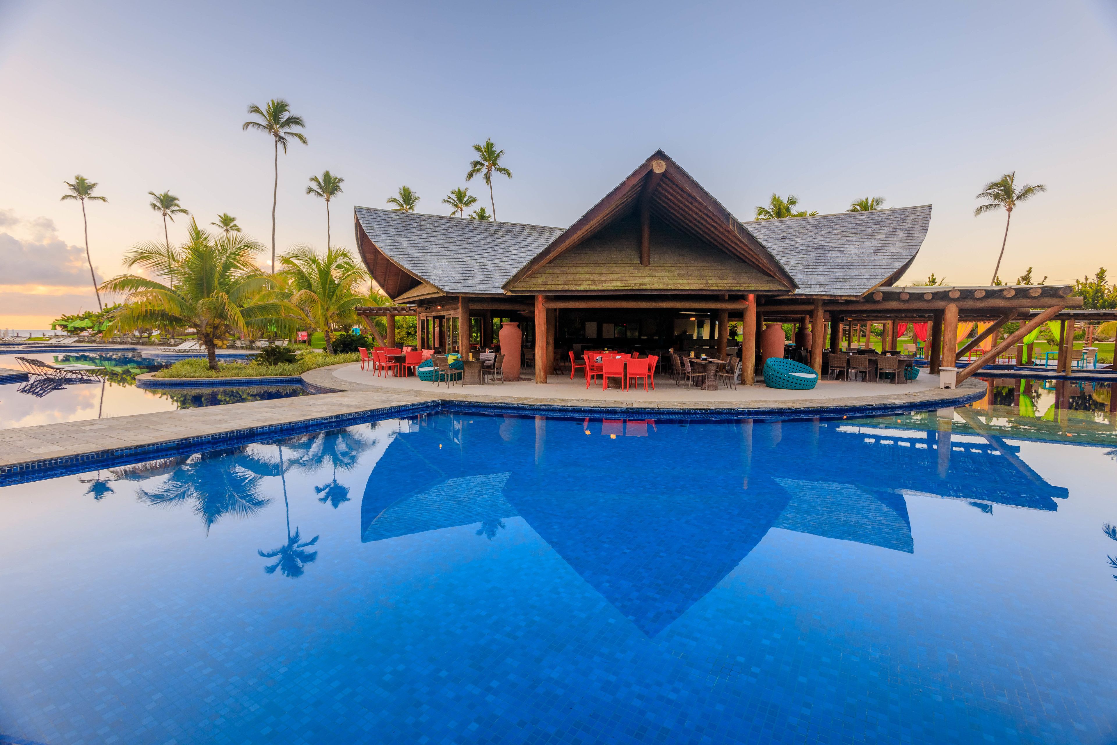 A resort with a large pool, outdoor seating, and palm trees.