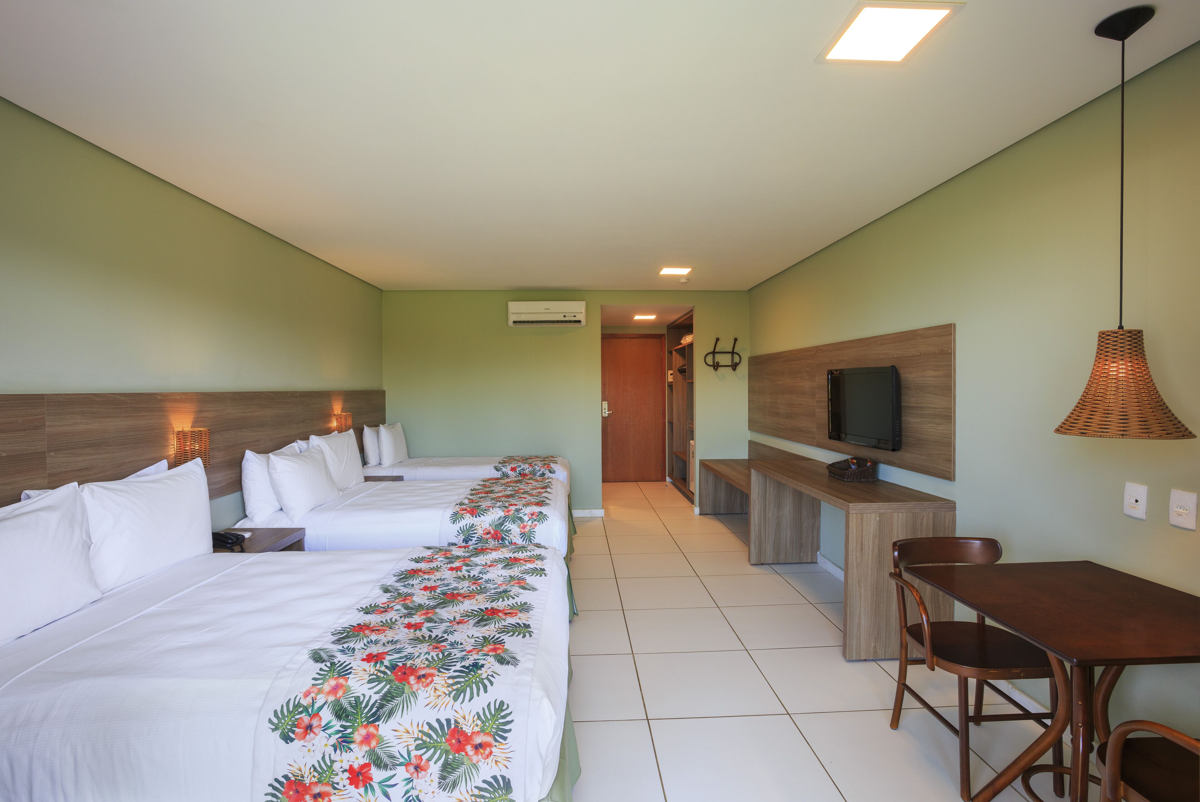 Habitación de hotel con dos camas, un escritorio de madera, un televisor y un rincón de comedor.