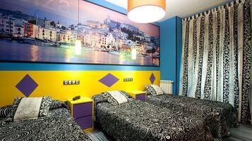 A hotel room with two beds, a large cityscape painting on the wall, and patterned curtains.