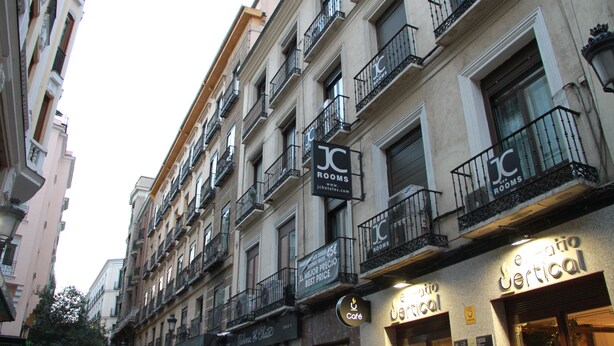 A multi-story building with "JC ROOMS" signage, balconies, and a cafe named "Café". - JC Rooms Santa Ana (Madrid)