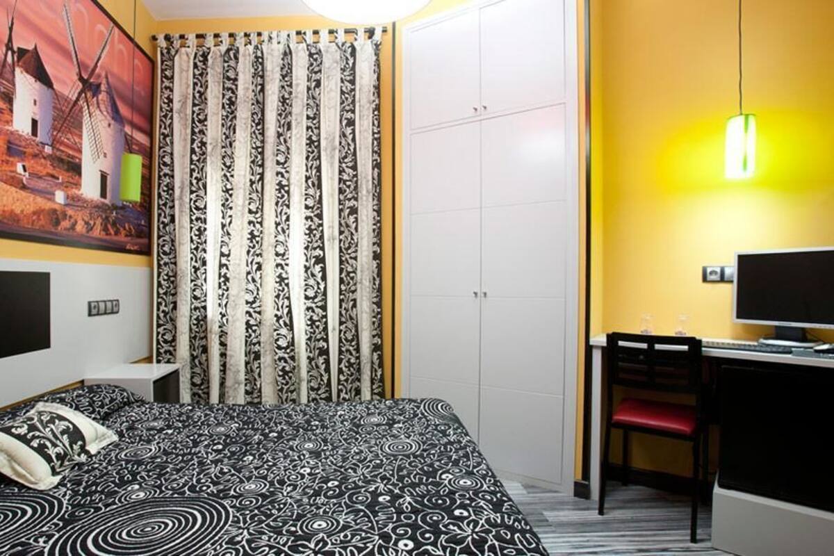 A bedroom with a bed, a desk, a chair, a television, and a wardrobe.