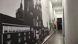 A hallway with a mural depicting a cityscape, including buildings and a train. - JC Rooms Santa Ana (Madrid)