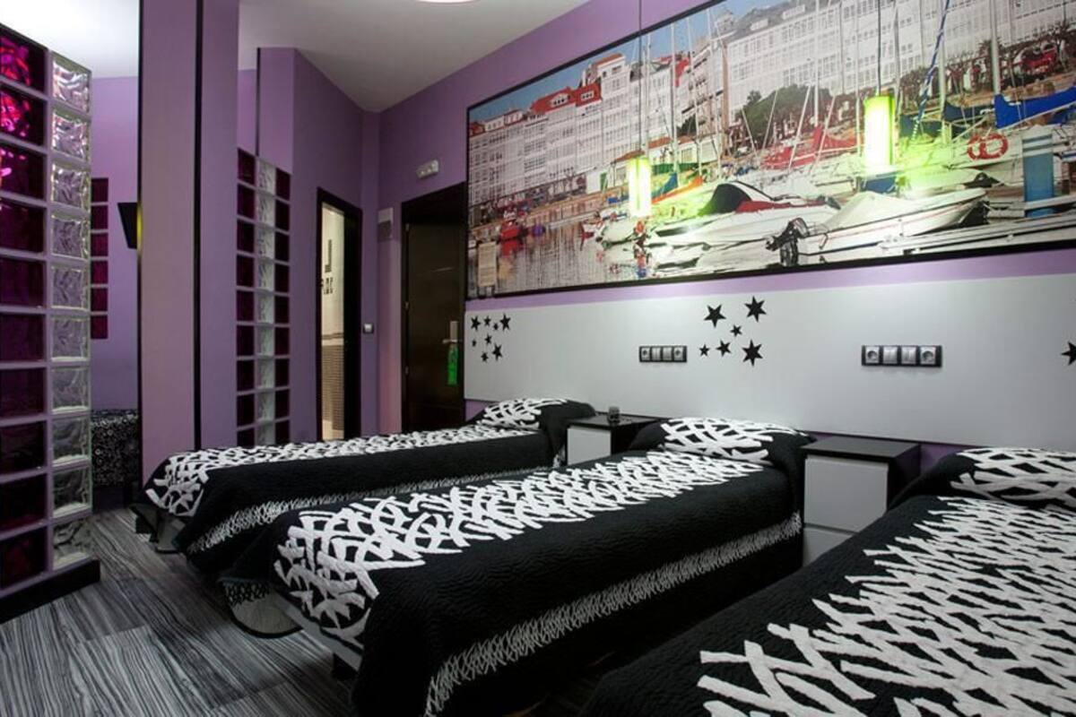 A room with three beds, purple walls, a large window, and a mural of boats.