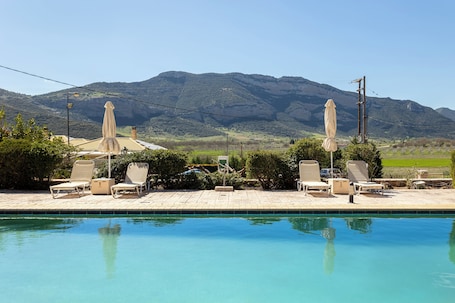 Una piscina al aire libre, sombrillas, sillones reclinables de piscina