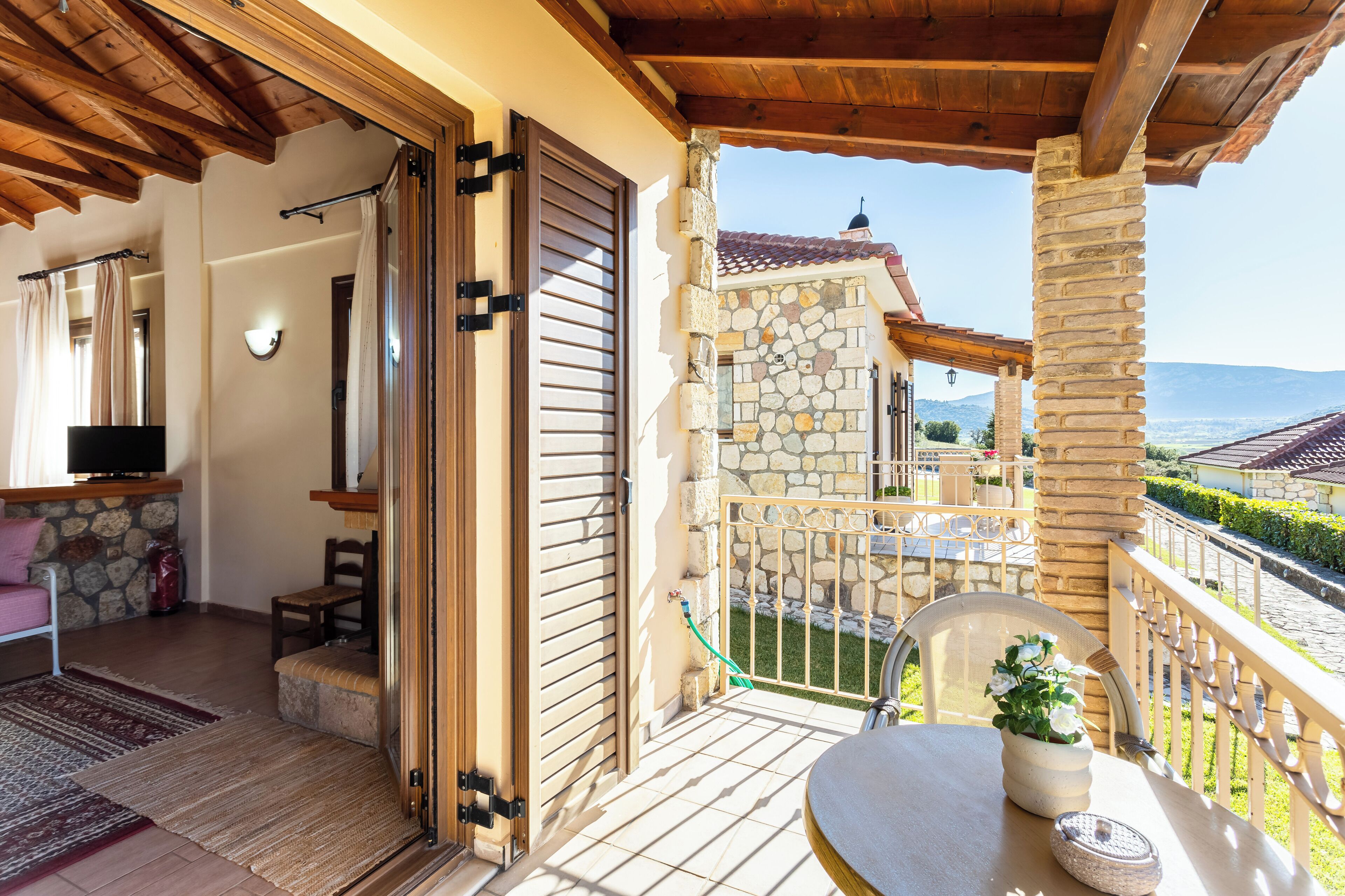 A balcony with stone walls, a wooden ceiling, and a view of the countryside.