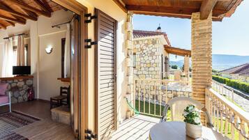 A balcony with stone walls, a wooden ceiling, and a view of the countryside.