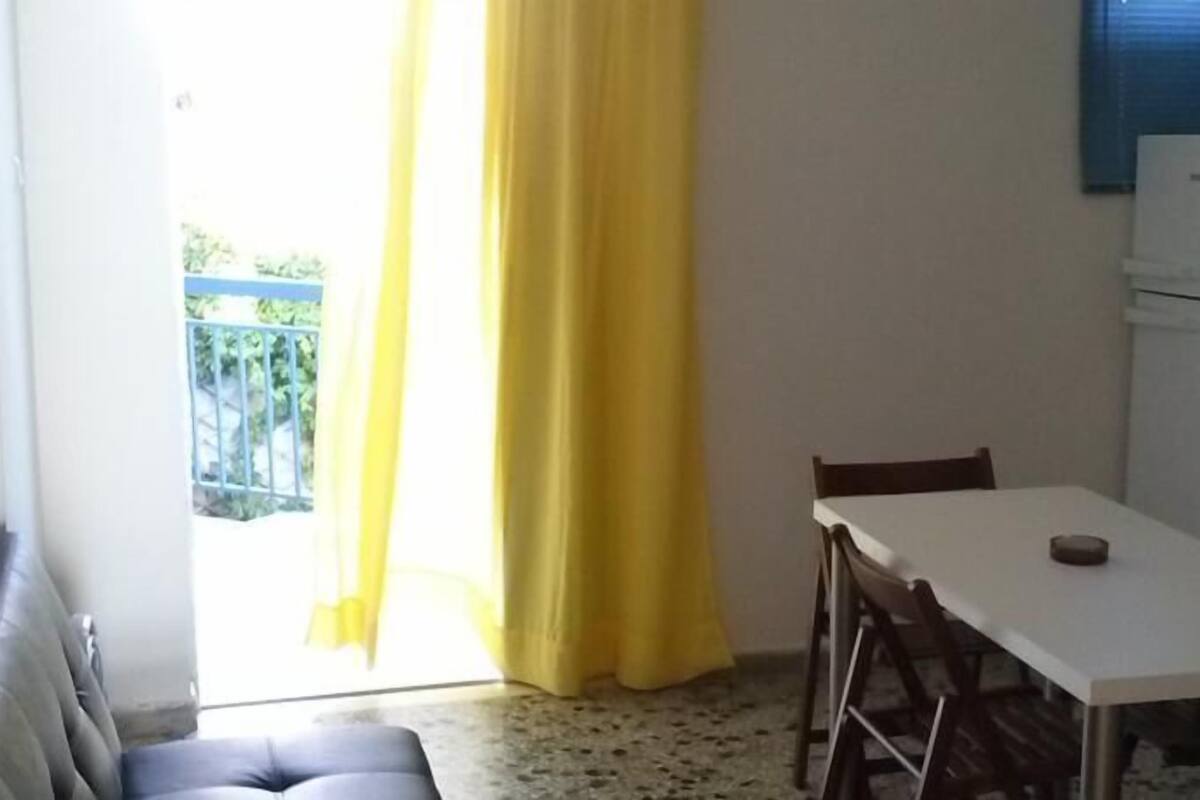 A small dining area with a table and chairs, a sofa, and a television on a cabinet.